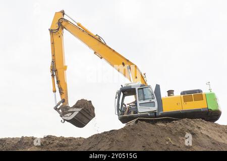 Bagger macht sandigen Hügel mit Boden Stockfoto