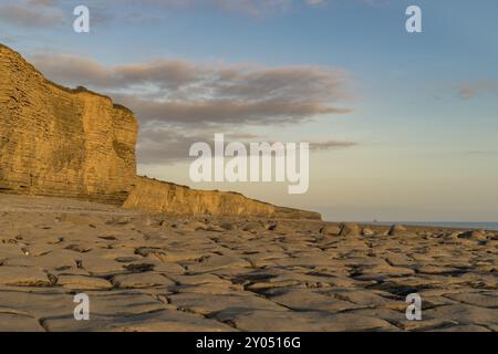 Die Steine und die Klippen von Llantwit Major Strand in der Abendsonne mit einigen Wolken über die Klippen, South Glamorgan, Wales, Großbritannien Stockfoto