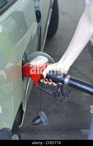 Frau filli bis Auto mit Gas an der Tankstelle Stockfoto