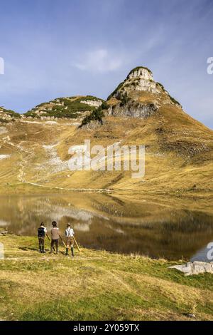 Das österreichische Alphorntrio Klangholz spielt das Alphorn am Augstsee am Mount Loser. Der Atterkogel im Hintergrund. Herbst, gutes Wetter, blau Stockfoto