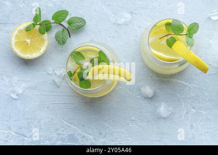 Limonade mit Minzpanorama. Zitronenwassergetränk mit Eis. Zwei Gläser und Zitronen auf pastellfarbenem Hintergrund, oberer Shot mit Kopierraum. Entgiftungsgetränk. Fres Stockfoto