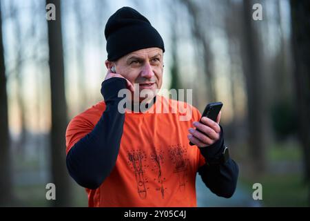 Läufer, der während des Laufens einen Anruf über Kopfhörer entgegennimmt oder Musik auflegt Stockfoto