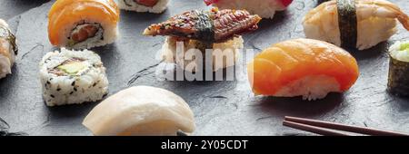 Sushi-Panorama. Brötchen, Nigiri auf schwarzem Hintergrund, japanisches Essen. Lachs und Aal mit Reis auf einem Teller in einem asiatischen Restaurant Stockfoto