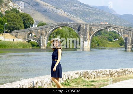 Eine weibliche Touristin vor der Arslanagic Bridge in Trebinje, Bosnien und Herzegowina. Eine Frau, die vor dem Hintergrund einer wunderschönen Brücke steht Stockfoto