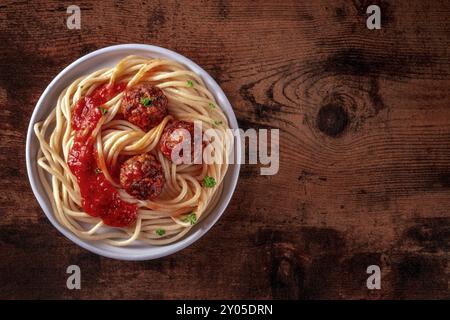 Fleischbällchen. Rindfleischbällchen, oben flacher Lay Shot mit Spaghettipasta, Petersilie und Tomatensauce, auf hölzernem Hintergrund, mit Kopierraum Stockfoto