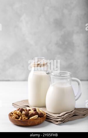 Gesunde natürliche nicht Molkerei Milch in ein Glas und Schüssel von Muttern auf weiße Holztisch, vertikal Stockfoto