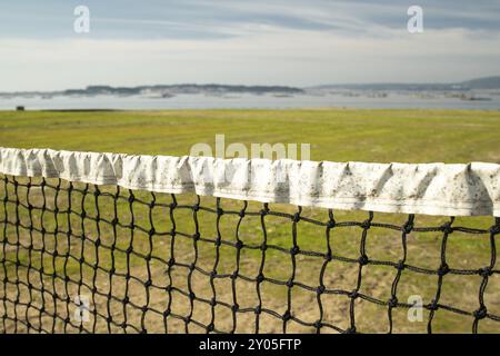 Beach Volleyball Net im Herbst mit Gras und alten net mit Defokussierten Meer Hintergrund Stockfoto