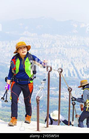 Seoul, Südkorea, 23. April 2015: Koreanische Frauen in farbenfroher Wanderkleidung nähern sich Baegundae, dem Gipfel des Bukhansan Berges mit Blick auf d Stockfoto