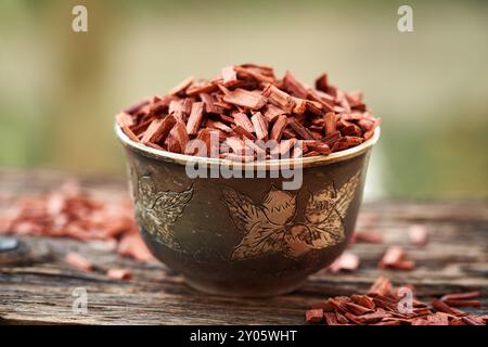 Rote Sandelholzspäne in einer Schüssel auf einem Tisch draußen. Inhaltsstoff für ätherische Öle. Stockfoto