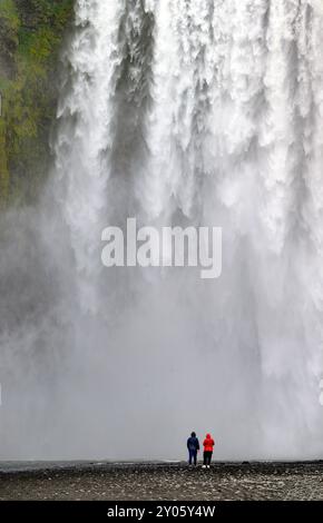 Touristen beobachten Skógafoss, einen spektakulären Wasserfall im Süden Islands. Stockfoto