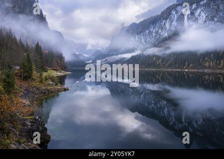 Der vordere Gosausee im Herbst mit Blick auf den Gosaukamm rechts. Der Dachstein in Wolken im Hintergrund. Bewölkter Himmel. Bewölkt. Reflexion. Stockfoto