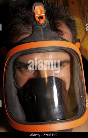 Ein schwarzhaariger Mann mit einer schwarz-orangen Atemschutzmaske Stockfoto