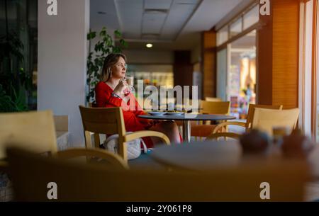 Mädchen in rotem Kleid trinkt Latte Kaffee. Stockfoto