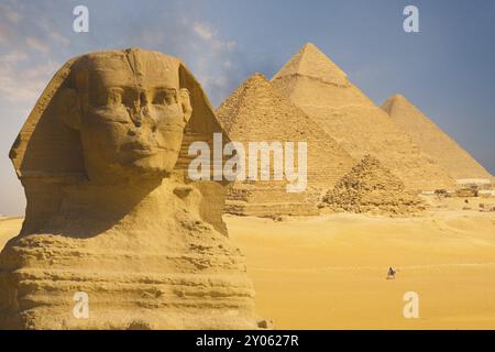 Eine Nahaufnahme des Gesichts der Großen Sphinx mit einer Reihe von Pyramiden im Hintergrund an einem wunderschönen klaren blauen Himmel in Gizeh, Kairo, Ägypten, Afrika Stockfoto