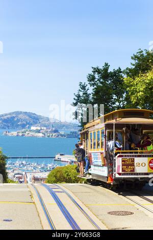 San Francisco, USA, 15. Mai 2016: Eine legendäre Seilbahn voller Passagiere auf dem Gipfel der Hyde Street, die über den Rand in Richtung Alcatraz I führt Stockfoto