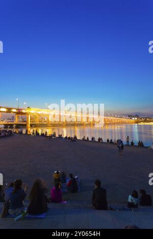 Die Menschen beobachten den Wasserbrunnen des Mondlichts Regenbogens und die farbenfrohe Lichtshow von der Banpo Bridge über den Han River in der Abenddämmerung in Gangnam, Seo Stockfoto