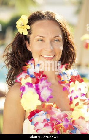 Junge lächelnde Frau in hawaiianischer Blumengirlande am Strand. Sommerurlaubskonzept Stockfoto