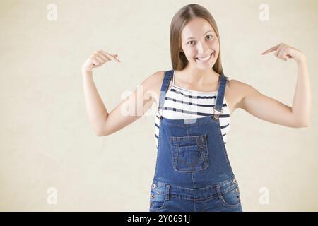 Glückliche Frau zeigt auf sich selbst isoliert in gelb Stockfoto