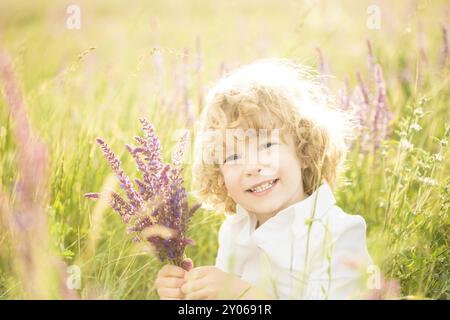 Glückliches Kind, das Frühlingsblumen draußen in der Hand hält Stockfoto