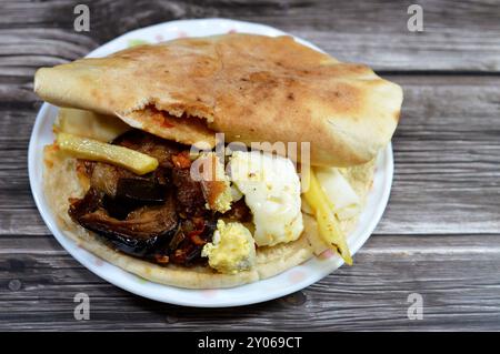 Mischung aus Kartoffeln, gebratenen Fingern, pürierten Fava-Bohnen, gebratener Aubergine, ägyptischem Falafel-grünen Burger, gekochten Eiern und Tahini gefüllt in einem Shami flatbre Stockfoto