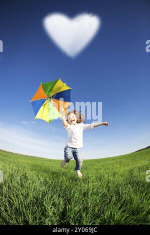 Glückliches Kind im grünen Feld gegen blauen Himmel springen. Sommer Urlaub Konzept Stockfoto