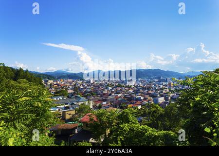 Luftaufnahme aus dem Wald am Stadtrand von Hida-Takayama-Gebäuden, Stadtlandschaft und umliegenden Bergen an einem Tag mit blauem Himmel in der Präfektur Gifu, Japan. Hori Stockfoto