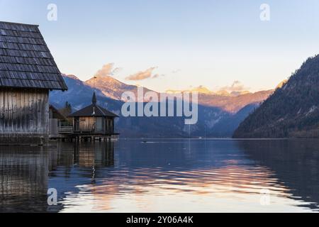 Grundlsee im Herbst bei Sonnenuntergang. Bootshäuser links, Berge im Hintergrund. Blauer Himmel, gutes Wetter. Grundlsee, Steiermark und Steirisches Salzkam Stockfoto