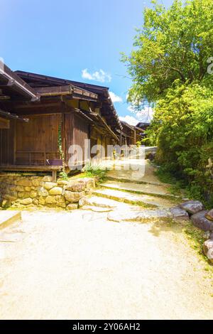 Eine schöne Reihe rustikaler Holzhäuser und unbefestigter Straße, die an einem sonnigen Tag auf der Nakasendo-Route im Dorf Tsumago zu einem alten Landgefühl restauriert wurde Stockfoto