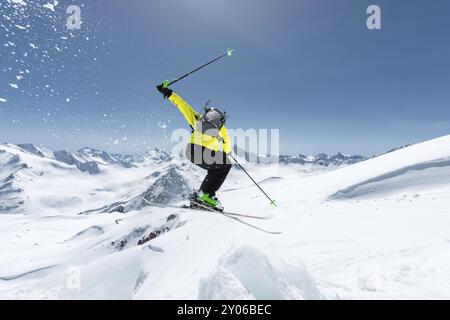 Ein Skifahrer in voller Sportausrüstung springt von der Spitze des Gletschers in den Abgrund vor dem Hintergrund des blauen Himmels und der kaukasischen Schneedecke Stockfoto