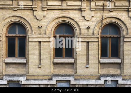 Drei alte Bogenfenster in einer Wand aus gelben Ziegeln. Grün, die Farben von Meereswellen-Glas in einem braunen dunkelroten Holzrahmen. Der Begriff des Antiken Stockfoto