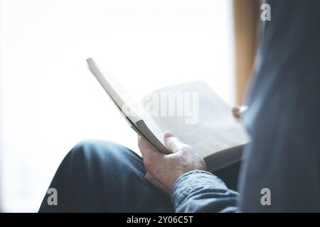 Schneiden Sie Bild von einem älteren Mann, der ein Buch zu Hause lesen Stockfoto