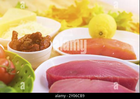 Rohes, appetitliches Thunfischfilet auf einem Tisch mit einem Hof griechischen Salat mit Lachs und Zitronengurken und Tomaten sowie Käse. Das Konzept von a d Stockfoto