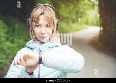 Porträt Junge Fitness-Frau, die ihre Smartwatch ansieht, während sie eine Pause vom Sporttraining macht. Sportsfrau überprüft Puls auf Fitness-Smartwatch d Stockfoto