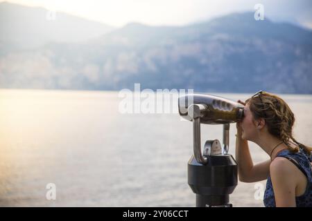 Schöne junge Mädchen mit blauen Kleid in den Ferien ist auf der Suche durchs Fernglas Stockfoto