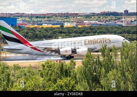 Madrid Spanien; 18.05.2024: Emirates Airline Flugzeug und Airbus A380 Modell landen auf der Landebahn hinter einigen Bäumen und verursachen beim Bremsen einen starken Rauch Stockfoto