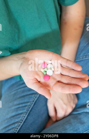 Mädchen, das Pillen hochhält. Verschiedenfarbige Pillen in einer Hand. Pillen aus einer Pillen-Flasche schütteln. Pillen aus Pillen-Blasen drücken. Stockfoto