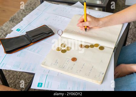 Blondes Mädchen mit finanziellen Problemen. Mädchen, das Steuern, Rechnungen und Rechnungen auf dem Tisch macht, Taschenrechner und Münzen. Ein bisschen Geld in der Brieftasche. Stockfoto