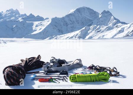 Winterausrüstung eines Eiskletterers mit Karabinerwunden und einer Camp-Thermos vor dem Hintergrund schneebedeckter Berge, Kopierraum für die Stockfoto