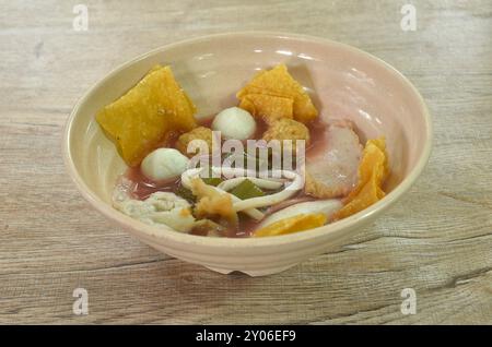 Gekochter Fisch und Garnelenkugel paar Knödel belegten eingelegten Tintenfisch in roter Sojasauce Suppe belegend gebratenes knuspriges gelbes Kloßmehl auf einer Schüssel Stockfoto