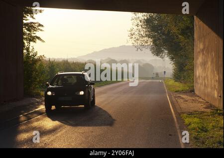 Das Auto fährt im Morgenlicht unter einer Brücke Stockfoto