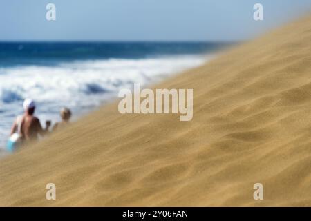 Älteres Paar, das in einem Sandsturm entlang einer Düne am Strand von Maspalomas spaziert Stockfoto