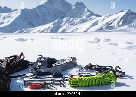 Winterausrüstung eines Eiskletterers mit Karabinerwunden und einer Camp-Thermos vor dem Hintergrund schneebedeckter Berge, Kopierraum für die Stockfoto
