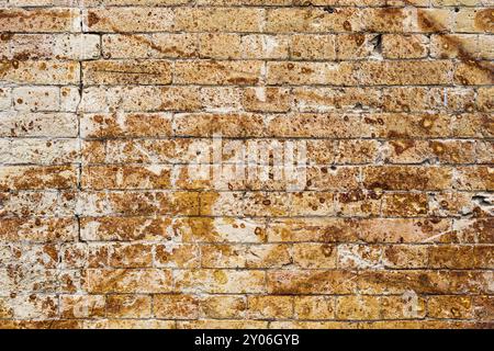 Hintergrundwand aus einem alten gelben Vintage-Backstein mit rostigen Korrosionsmustern auf der Oberfläche. Strukturierter Hintergrund im Grunge-Stil. Beschaffung für Stockfoto