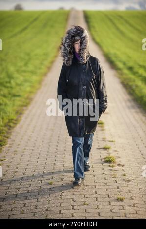 Eine Frau läuft auf einem Weg zwischen zwei Feldern Stockfoto