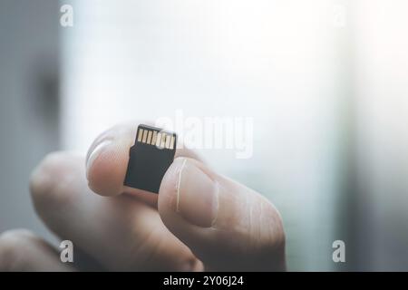 Der junge Mann hält eine kleine Speicherkarte in der Hand, Textraum Stockfoto