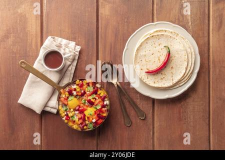 Mexikanisches Frühstück. Huevos Rancheros, Spiegeleier, von oben mit Pico de gallo Salat, heißer Schokolade und Tortillas auf einem dunklen rustikalen Holz geschossen Stockfoto