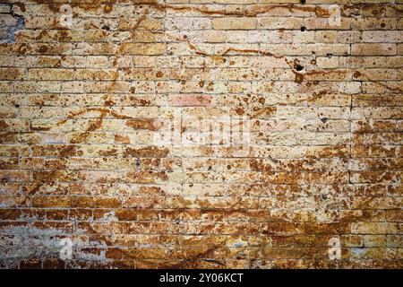 Hintergrundwand aus einem alten gelben Vintage-Backstein mit rostigen Korrosionsmustern auf der Oberfläche. Strukturierter Hintergrund im Grunge-Stil. Beschaffung für Stockfoto