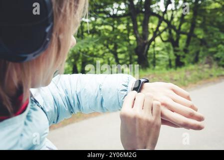 Junge Fitnessfrau, die ihre Smart Watch ansieht, während sie eine Pause vom Sporttraining macht. Sportsfrau überprüft Puls auf Fitness-Smart-Watch-Gerät in Stockfoto