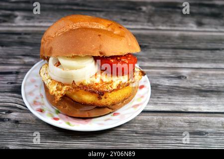 Gebratener Hähnchenburger, gekocht in einem kochenden Flachöl mit Tomatenscheiben, Zwiebeln, Spiegelei mit Paprika in einem Brötchen, Fast Food, Junk-Food-Konzept, Stockfoto