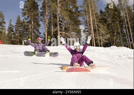 Zwei Freunde sitzen auf den Skipisten, Snowboardermädchen Stockfoto